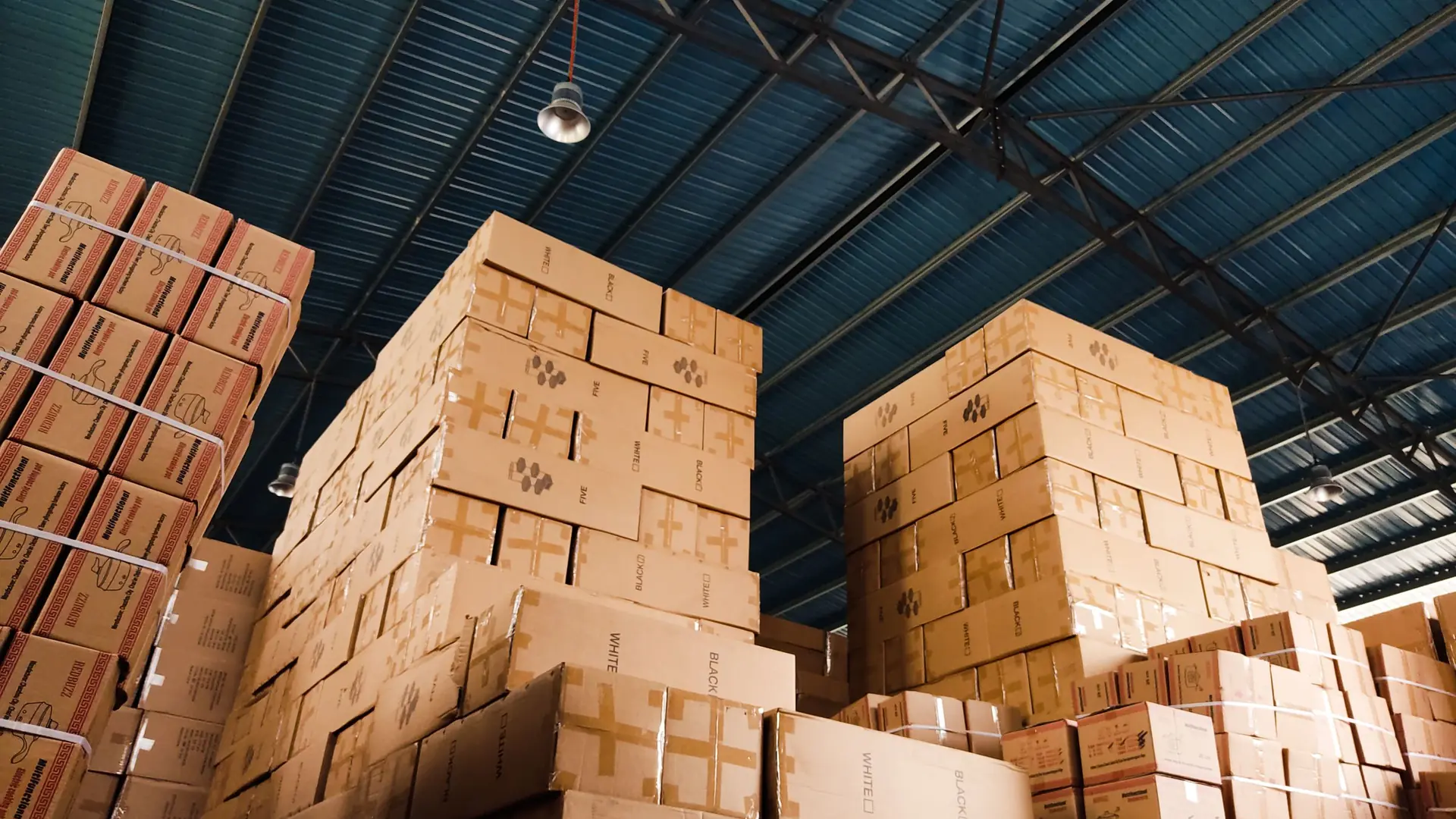 Tall stacks of cardboard mystery-box inventory in warehouse